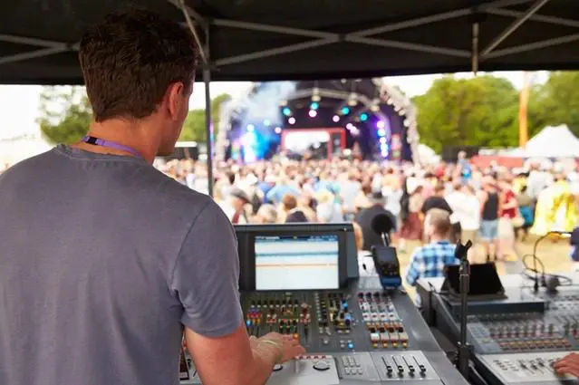 A man is working on an audio mixing board.