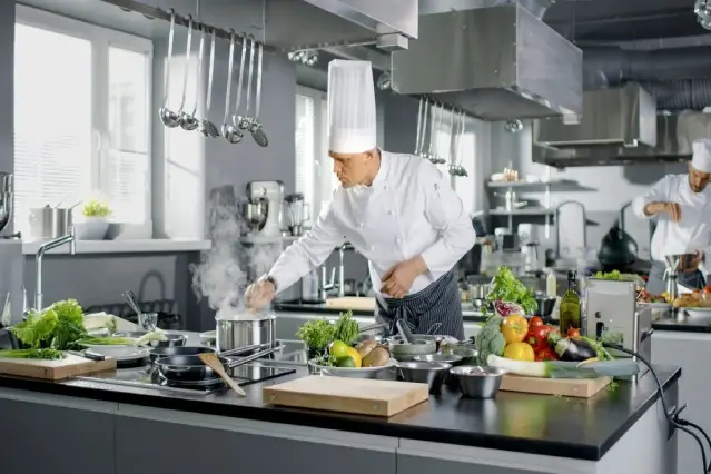 A chef in the kitchen preparing food for people.