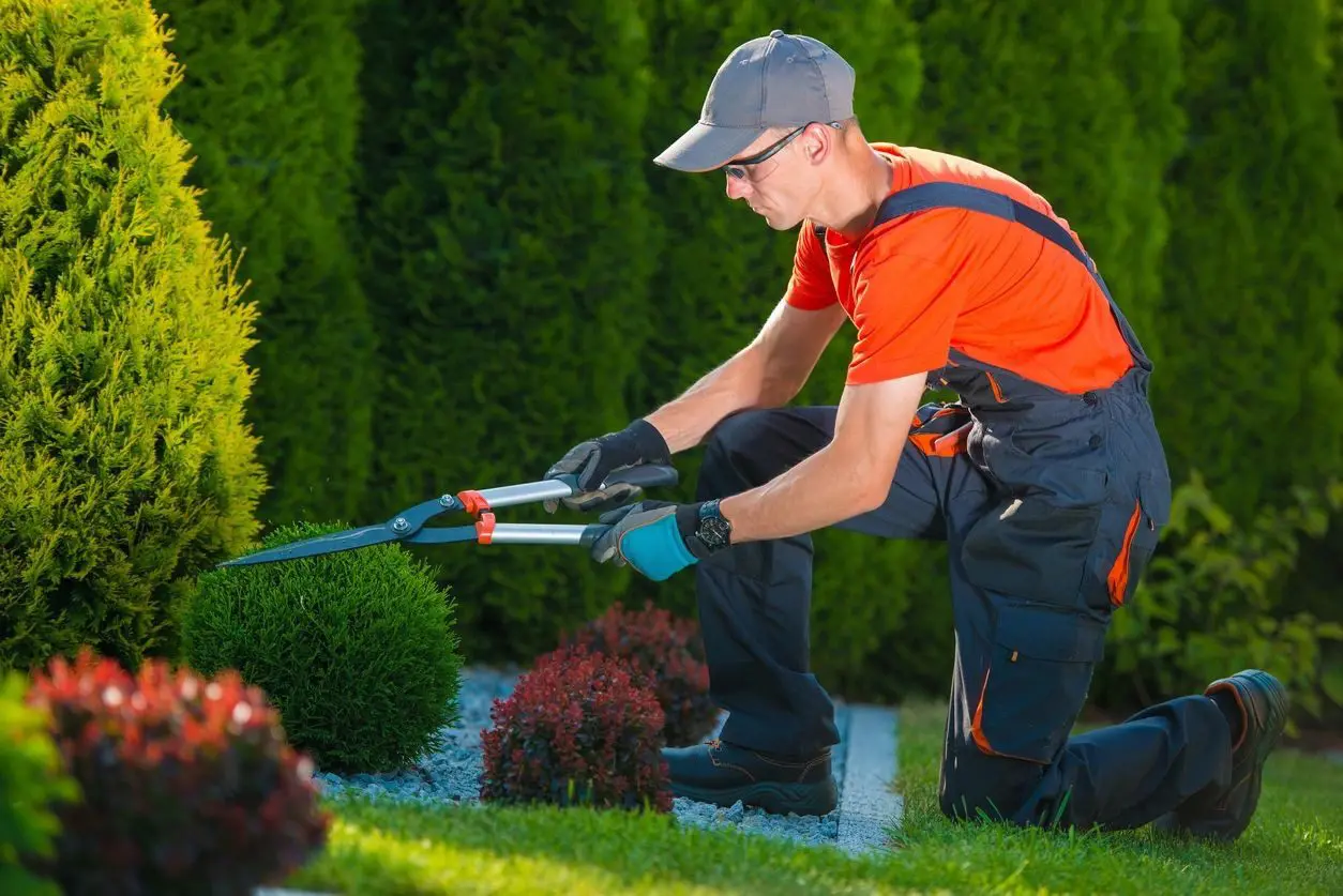 A man in an orange shirt holding a hose.